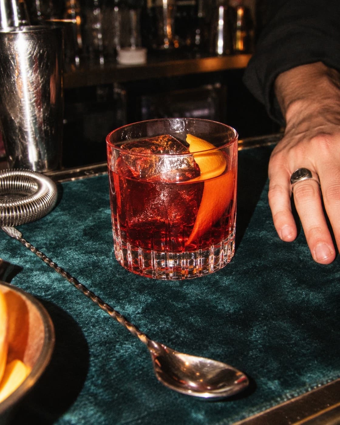 A deep amber-red boulevardier in a short tumbler on a white marble ledge against a warm cream wall