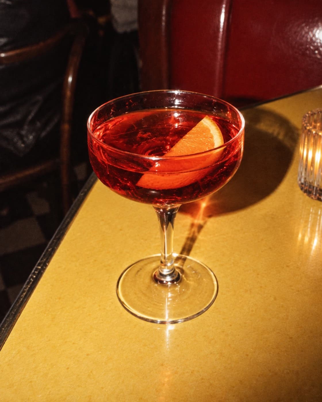 A sparkling red-orange sbagliato full of bubbles in a tall stemmed glass, in soft daylight